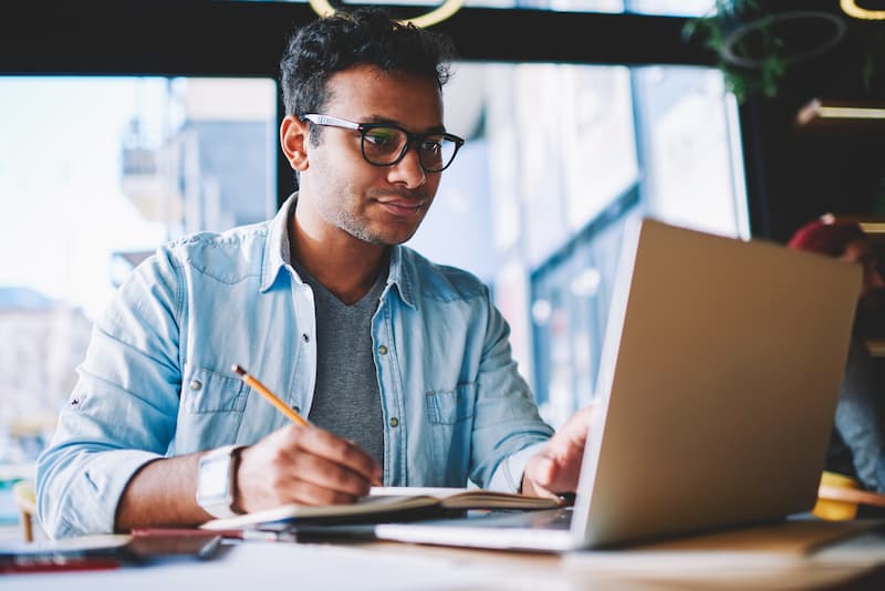 A man studying with a laptop and notepad