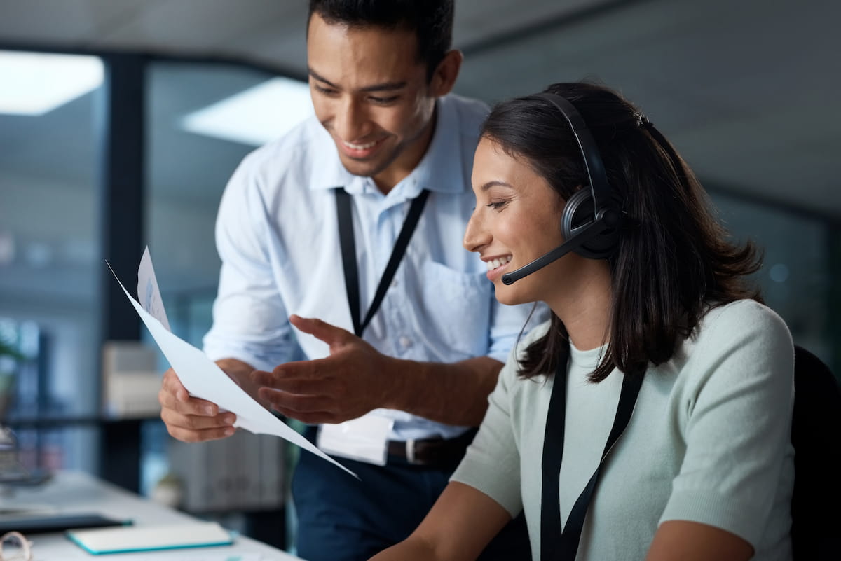 Two agents looking at a script while one is talking into a headset