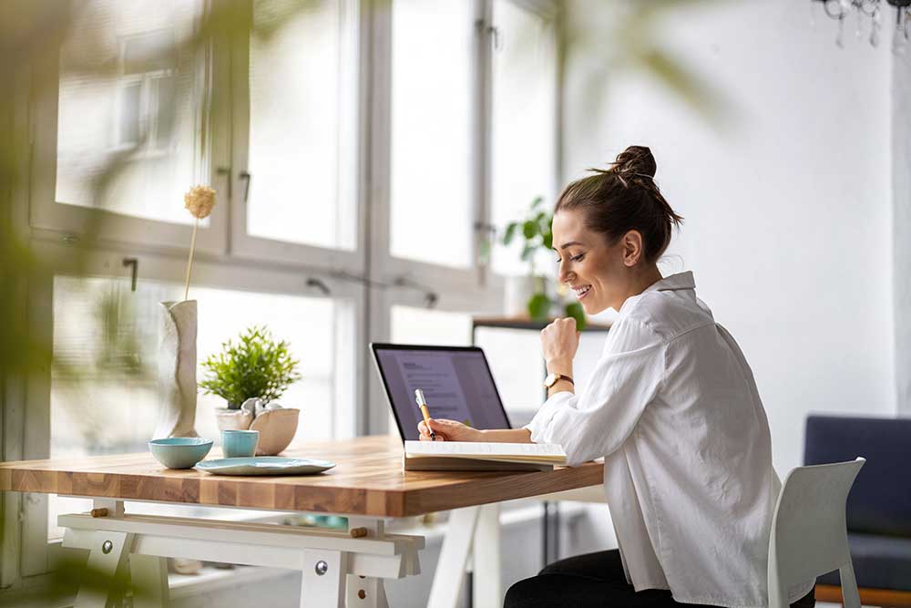 A woman sitting at a desk by a large window